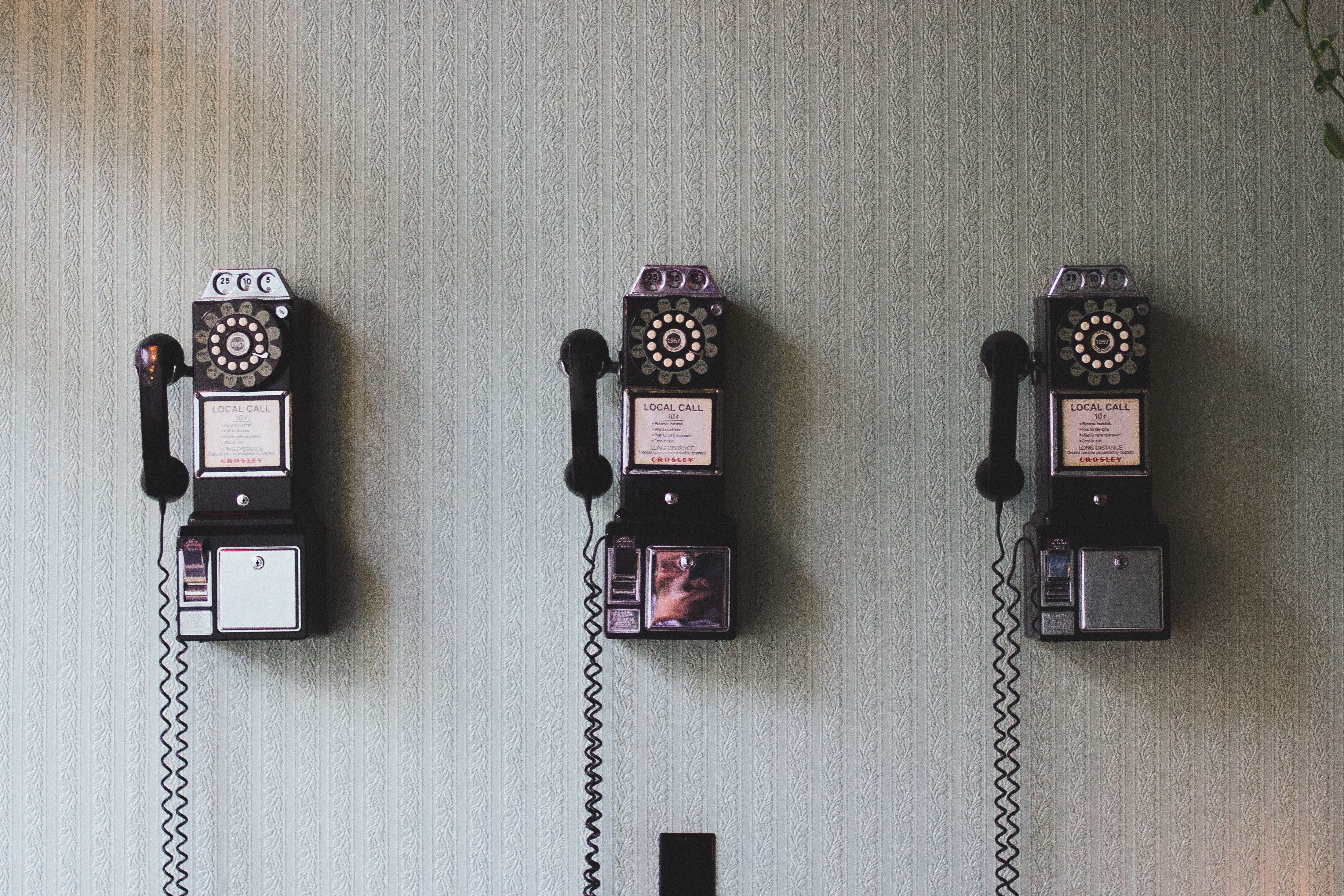 Kontakte und Anmeldungen, Bild von 3 alten Telefonen an der Wand als Sinnbild für Kontakte
